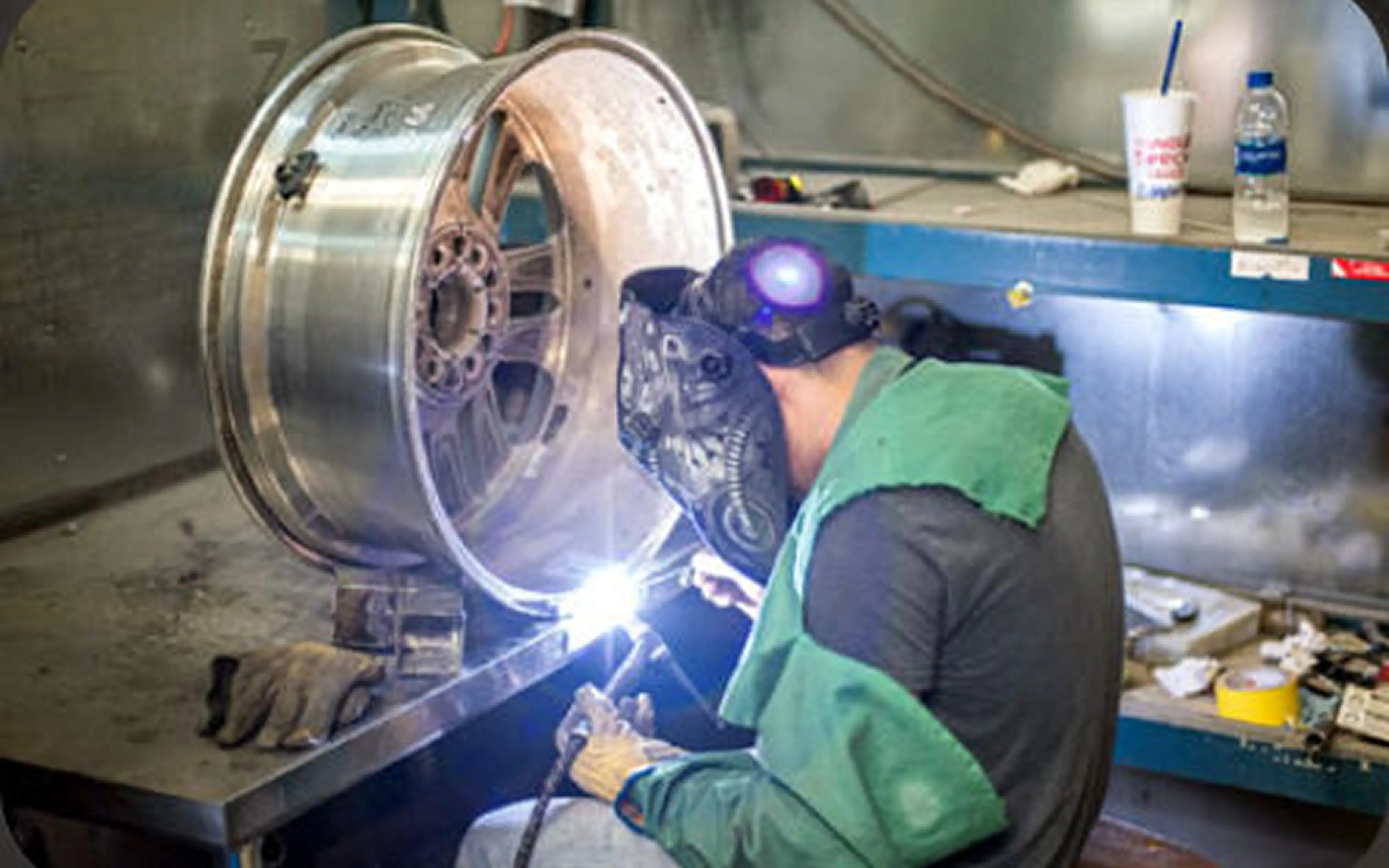 Welder repairing a metal wheel rim.