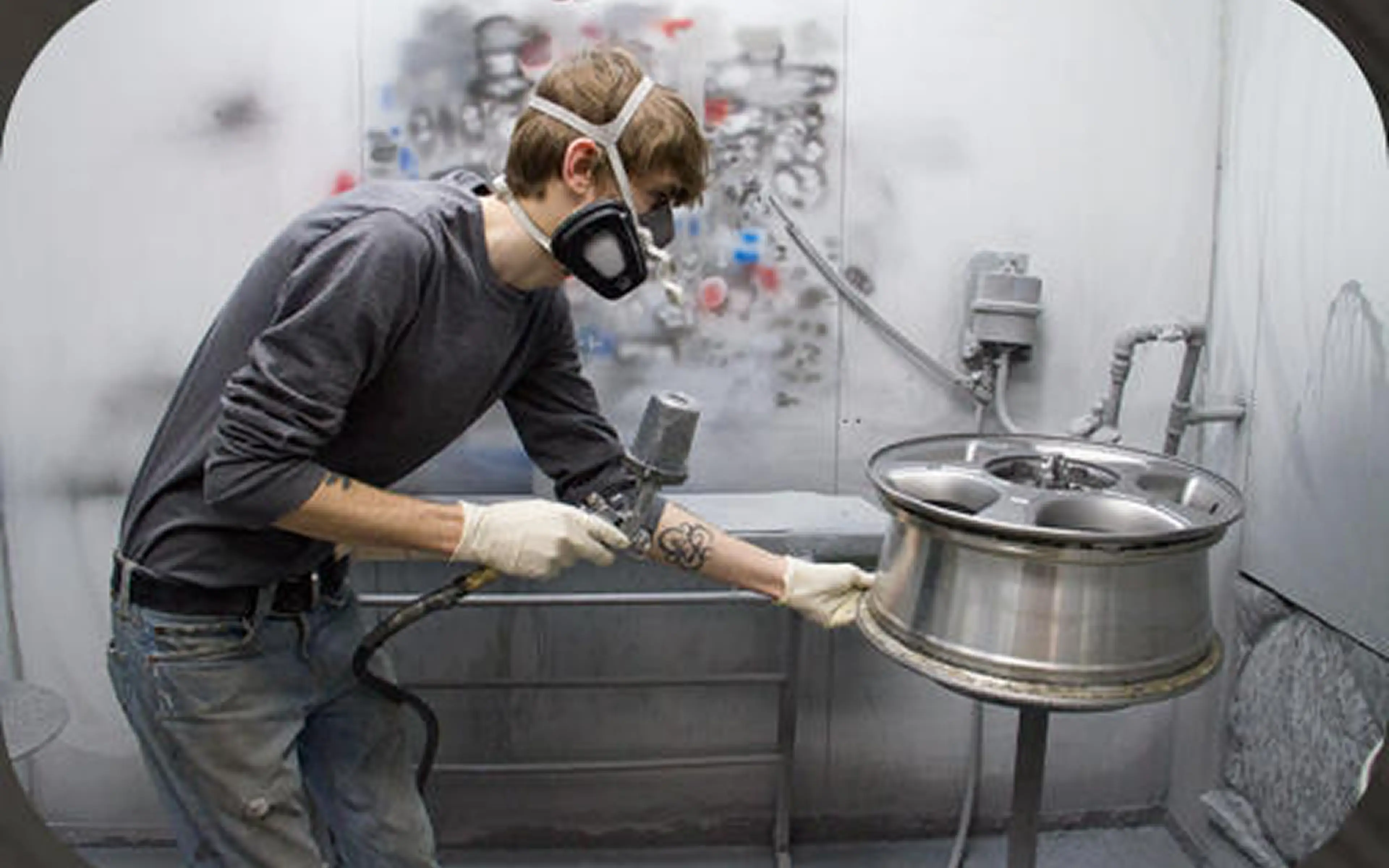 Person spray painting a car wheel rim.
