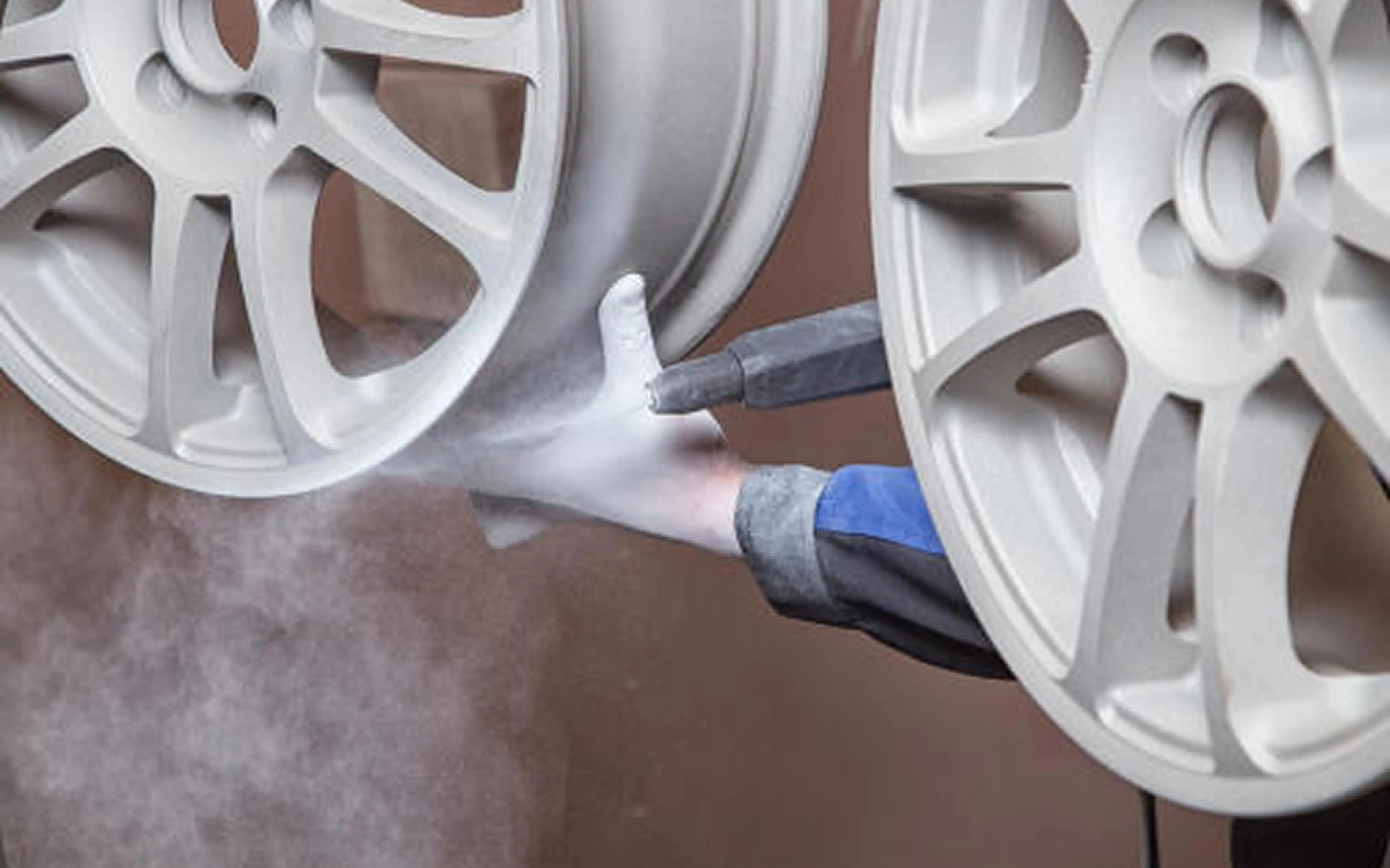 Spray painting car rims in workshop.