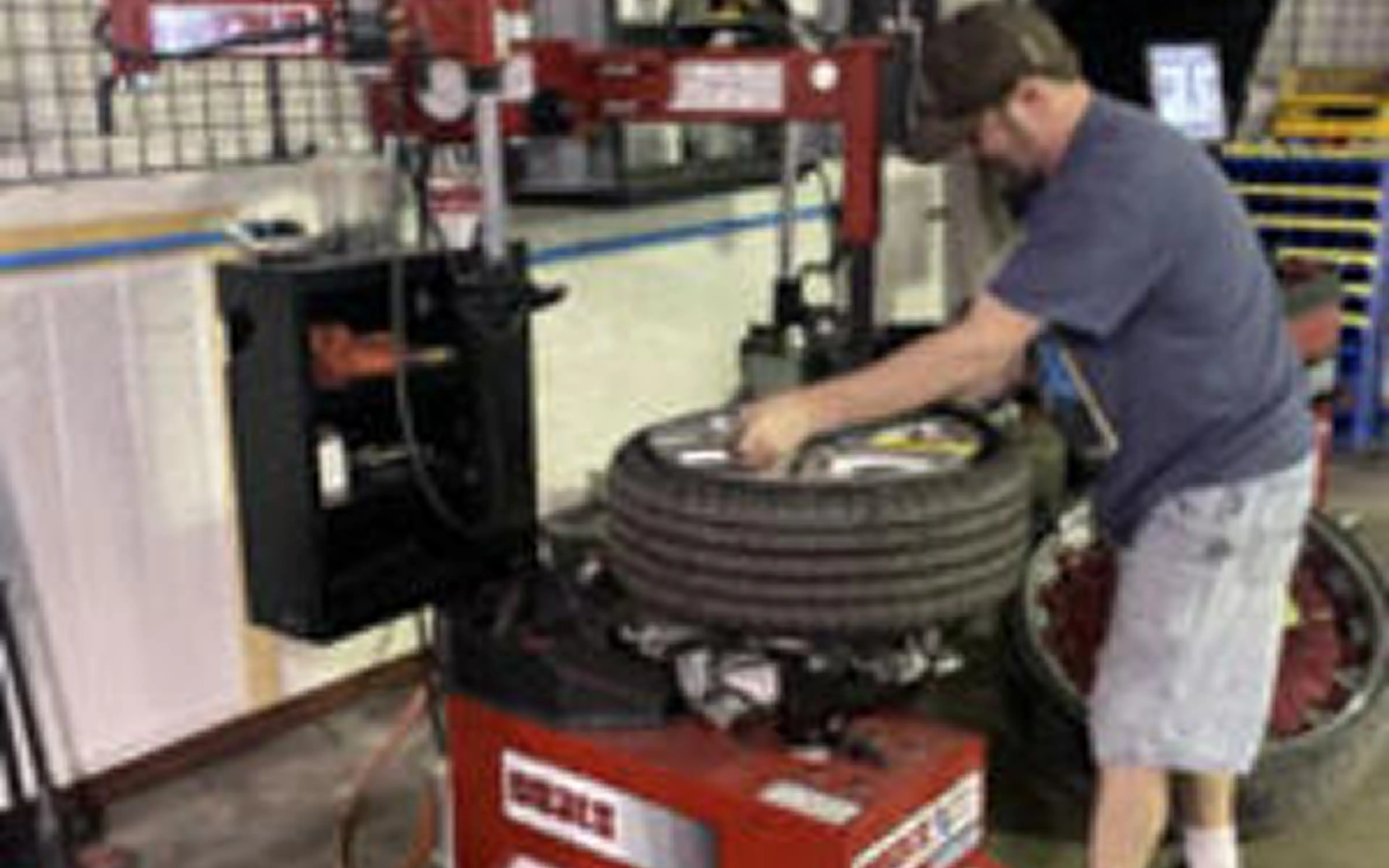 Man operating tire-changing machine in workshop.