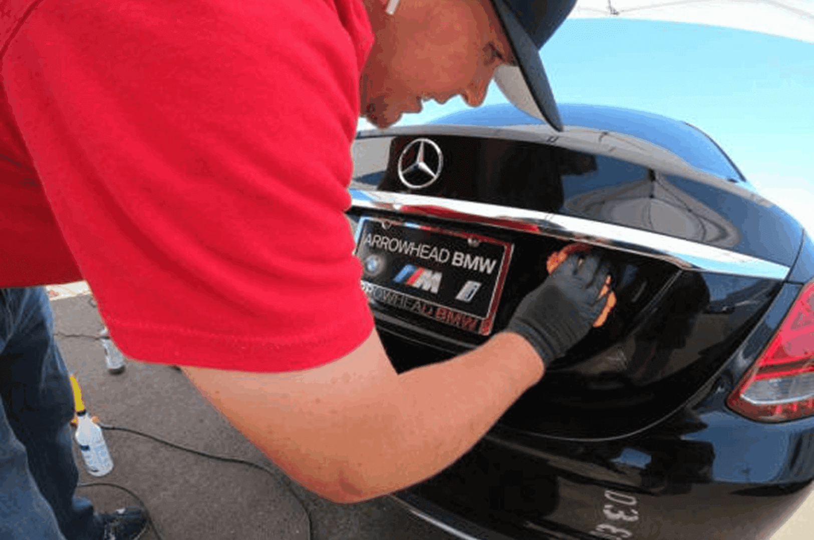 Man polishing black car with Mercedes emblem.
