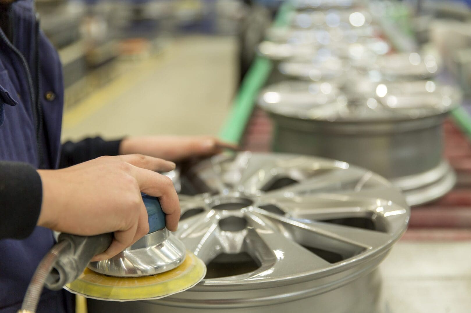 Person polishing a car wheel rim.